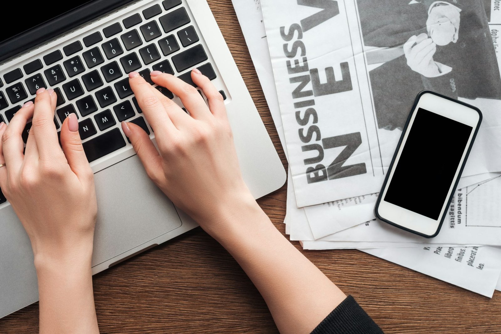 cropped image of journalist working at laptop at wooden table